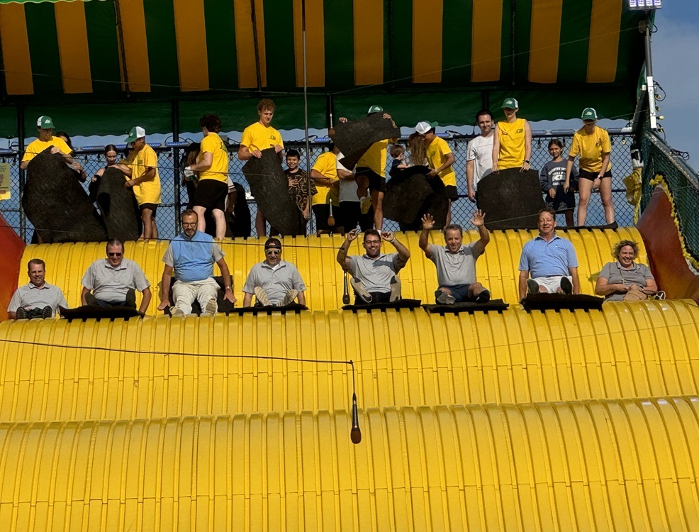 8 members of the Fishbowl Solutions team going down a giant slide at the state fair